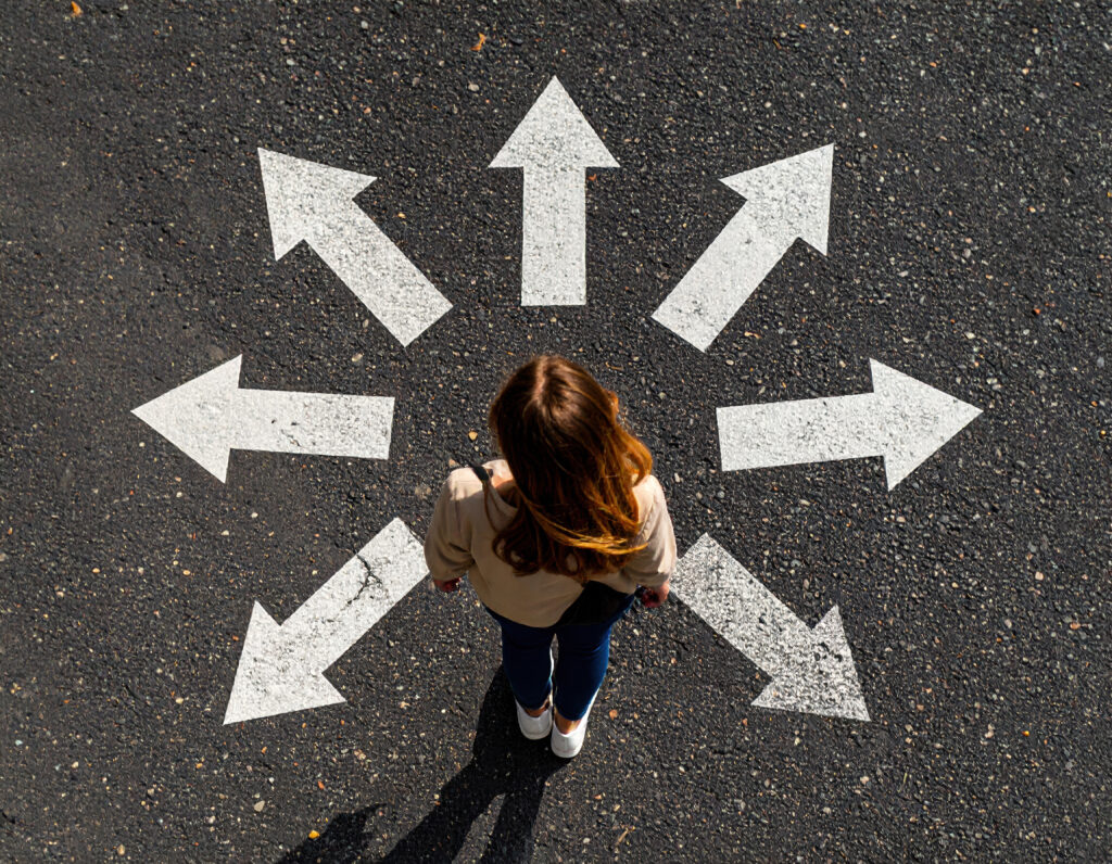 Top view of a woman standing in the middle of a road surrounded by arrows Free Photo