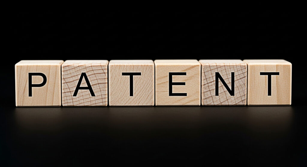 Text "PATENT" spelled out with wooden blocks against a black background. The blocks are neatly aligned, conveying a sense of order and professionalism.